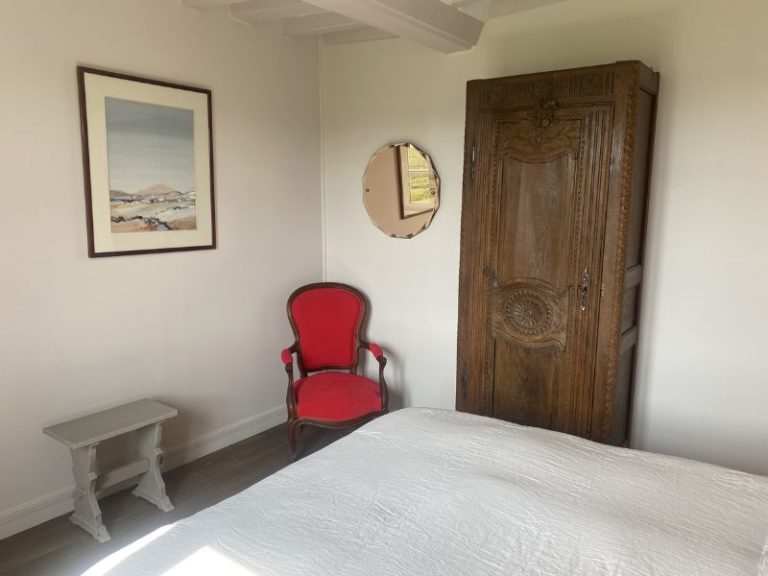 Armoire normande en chêne sculpté et fauteuil rouge de la chambre La Bonbonnière