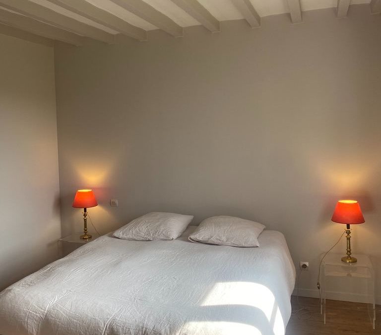 Lit double, poutres blanchies et lampes de chevet dans la chambre La Bonbonnière