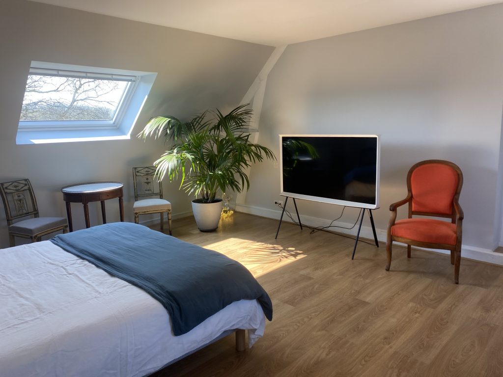Chambre des combles avec lit king size sous les colombages blanchis