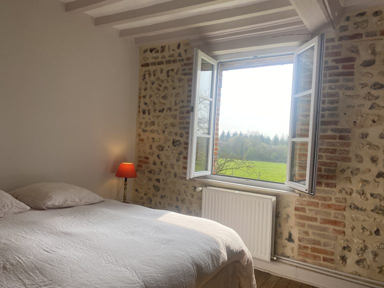 Chambre aux murs de brique et silex ouverte sur la campagne