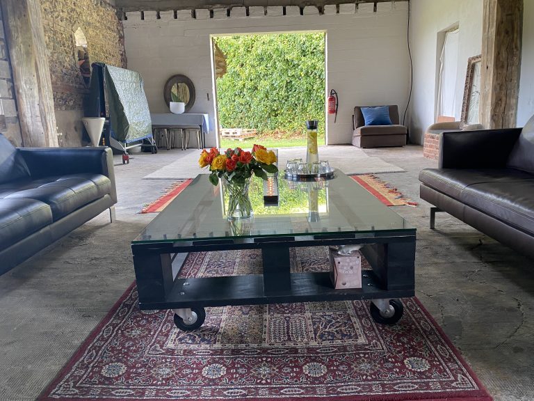 Grande salle de l'ancienne grange, murs de silex et canapés, pour ateliers et séances de yoga