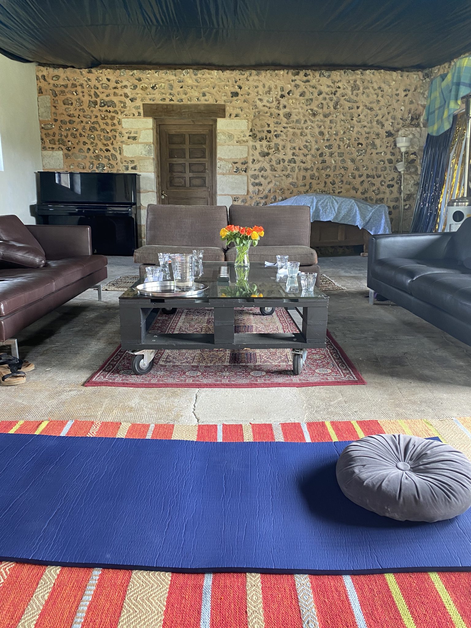 Tapis déroulés dans la grande salle de la grange pour une séance de yoga