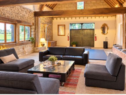 Grande salle voûtée de la grange, poutres apparentes et tapis de sol bleu, aménagée pour un stage de yoga