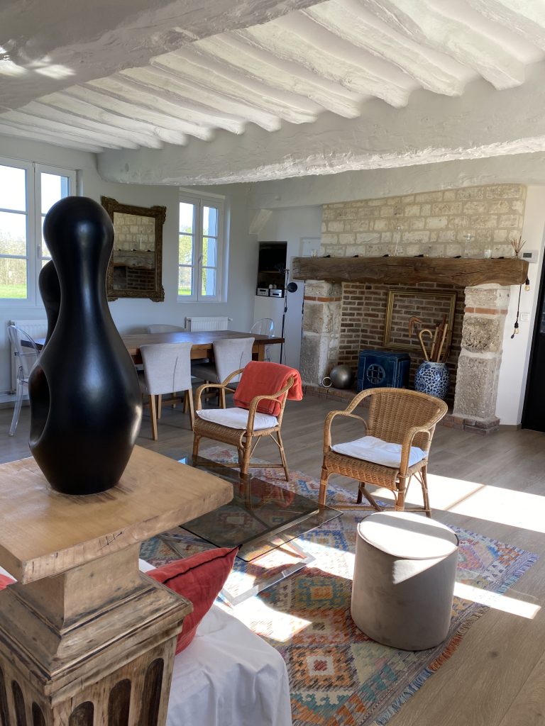 Séjour et cheminée de pierre vus depuis la salle à manger